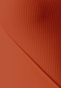 Tela acanalada en un naranja profundo, con un diseño diagonal que presenta texturas variadas. La superficie es suave con un acabado ligeramente blando.