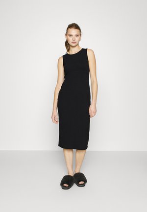 Abito midi a coste nere con design senza maniche. L'abito presenta una silhouette aderente e un collo a giro. Abbinato a pantofole nere in peluche.