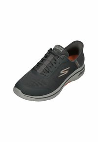 Skechers Go Walk Schuh aus dunkelgrauem Mesh-Material mit strukturierter Oberfläche, ausgestattet mit grauen Schnürsenkeln, orangefarbenen Akzenten und einer gepolsterten Sohle.