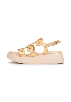 Złota sandałka na platformie z wycięciami w kształcie serca, regulowanym paskiem na kostkę i grubą beżową podeszwą.
