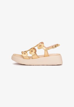 Sandalia de plataforma dorada con recortes en forma de corazón, correa ajustable en el tobillo y suela gruesa beige.