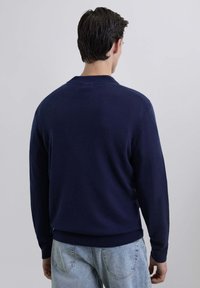 Suéter de punto azul marino con cuello redondo y dobladillo acanalado. Presenta mangas largas y una textura suave. Diseño casual adecuado para superponer.