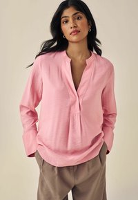 Blusa rosa chiaro con scollo a V profondo e maniche lunghe, caratterizzata da un fit rilassato, design senza colletto e dettagli di cucito sottili.
