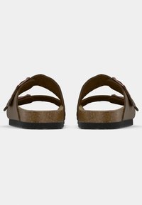 Bruna två-rem sandaler med korkfotbäddar och svarta såler, visade bakifrån mot en enfärgad vit bakgrund.