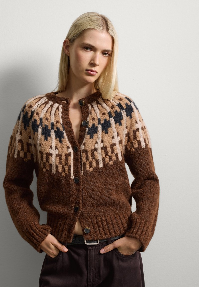 Bruine gebreide cardigan met een gepatternde yoke in beige en marineblauw, voorzien van een knoopsluiting en ribbelhem, met een textuur van warm materiaal.