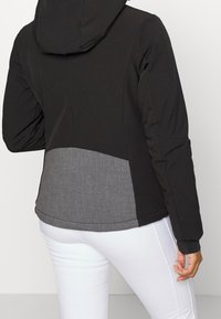 Czarna kurtka z kapturem z szarymi, teksturowanymi akcentami w talii. Charakteryzuje się gładkim wykończeniem, długimi rękawami i luźnym krojem.