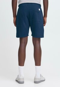 Pantalones cortos de sudadera azul marino con un ajuste relajado, que cuentan con un bolsillo trasero y una cintura elástica. Fabricados con un tejido suave de textura lisa.