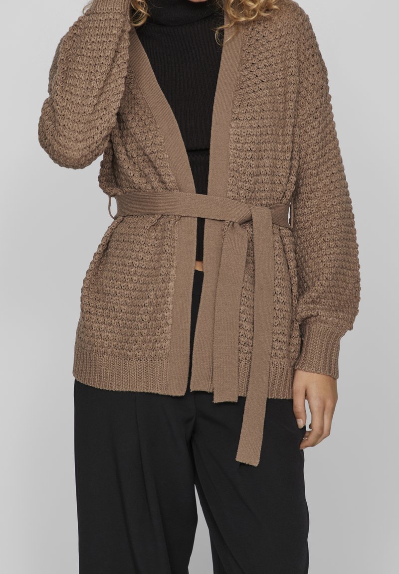 Cardigan tricoté en taupe avec un design texturé, à l'avant ouvert, à manches longues et une ceinture en tissu assortie à la taille.