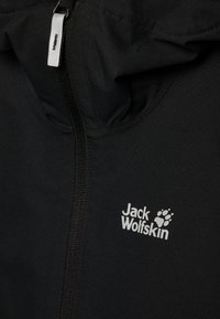 Black jacket with a front zipper and hood. Features a white logo "Jack Wolfskin" and a paw print. Material appears soft and textured.