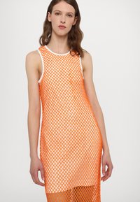 Robe en résille orange avec un design sans manches, un col rond et une longueur plus longue avec une texture superposée.