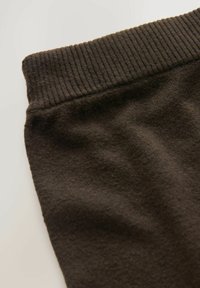 Brauner Baumwollmischgewebe-Stoff mit einem gerippten Bund, der eine weiche Textur und eine glatte Oberfläche zeigt, gefaltet, um seine Form und Designmerkmale hervorzuheben.