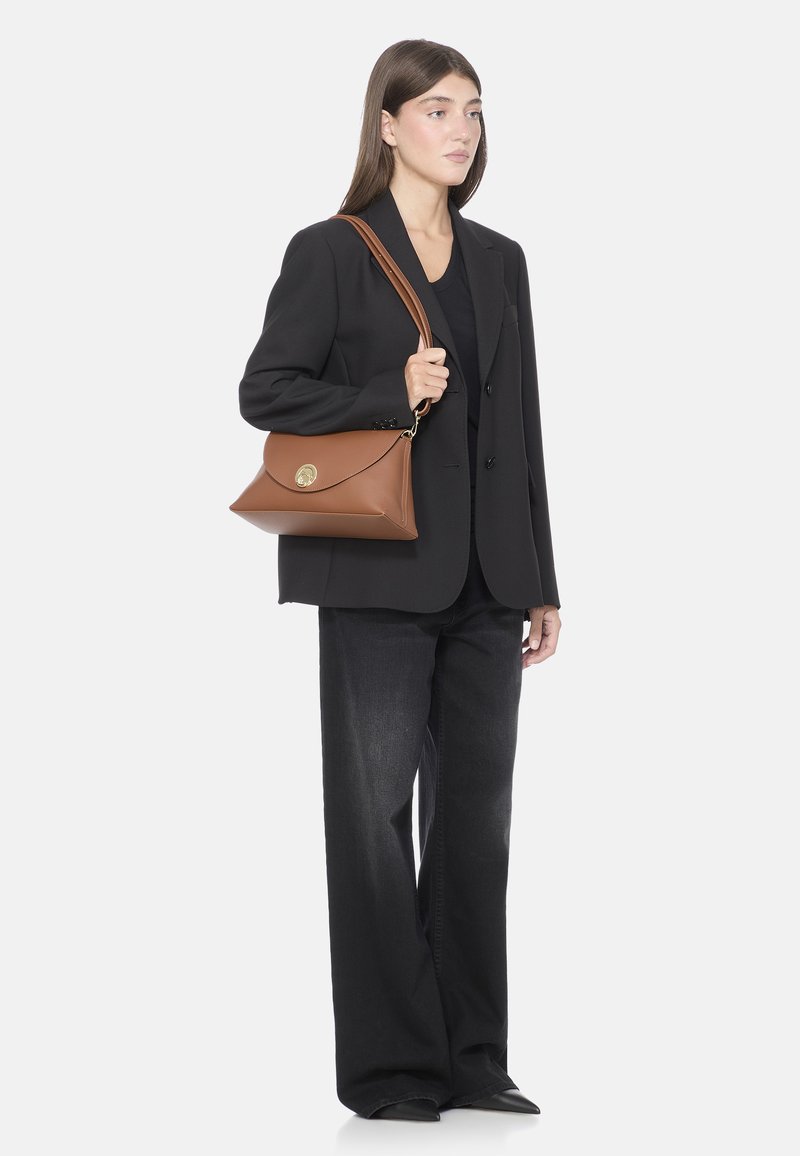 Borsa a tracolla in pelle marrone con pattina triangolare, hardware dorato, lunga tracolla, materiale testurizzato e design minimalista.