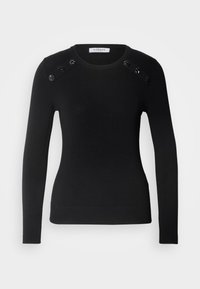 Černý svetr s dlouhými rukávy, kulatým výstřihem, žebrovaným spodním lemem a zdobenými detaily na ramenou, které mají černé dekorativní akcenty. Měkký pletený materiál.