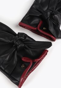 Czarne skórzane rękawiczki z czerwonymi akcentami, z węzłowym wzornictwem i zapięciem na zatrzask. Gładka tekstura i uporządkowany kształt.