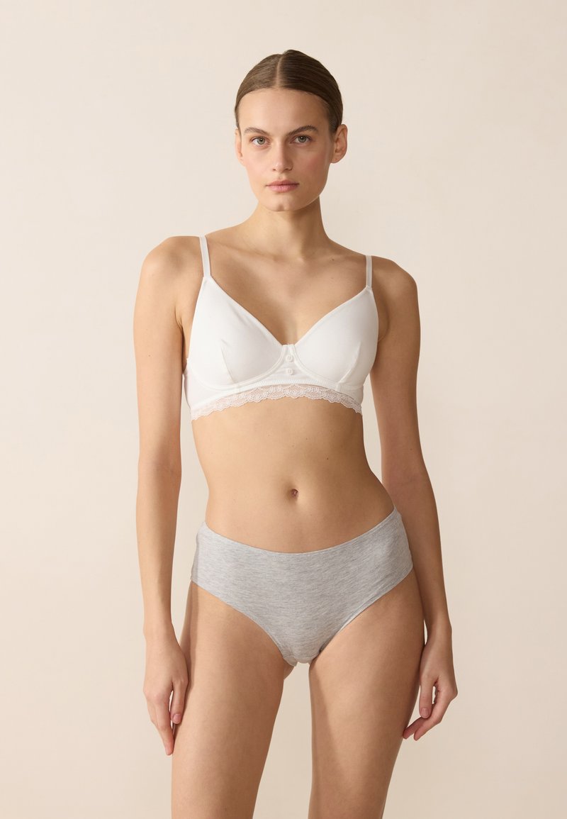 White cotton bra with lace trim, featuring adjustable straps and button details. Paired with light gray cotton high-waisted briefs.
