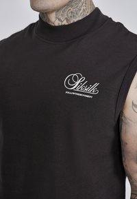 Black sleeveless top made of smooth fabric featuring a high collar and a white logo with the text "FOLLOWTHEMOVEMENT" near the chest.