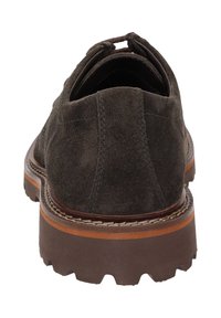 Chaussure en daim marron au design arrondi, avec une tige texturée et une semelle en caoutchouc marron solide. Présente un bord cousu et une languette au niveau du talon.