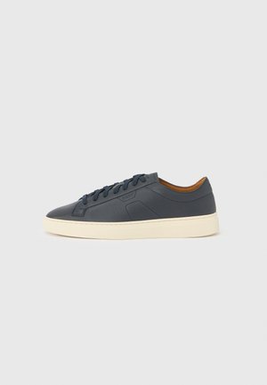Navy leather sneaker with a cream sole, featuring lace-up closure, rounded toe, and minimalist design elements including tonal accents.
