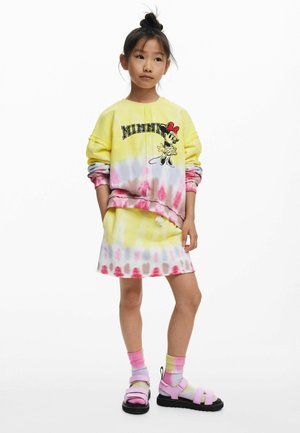 Tie-dye sweatshirt with yellow, pink, and white colors featuring Minnie Mouse graphic. Paired with a matching skirt and pastel sandals.