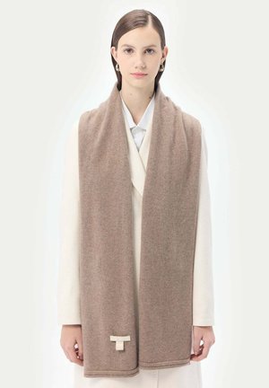 Écharpe en laine beige avec une texture douce, ornée d'un bord cousu et d'une petite étiquette de marque en bas. Drapée élégamment autour du cou.