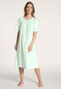 Camicia da notte verde menta realizzata in tessuto morbido, con maniche corte, scollatura rotonda e dettagli plissettati sul busto. Design casual e fluido.