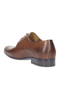 Scarpa da uomo in pelle marrone con punta arrotondata, texture liscia e finitura naturale. Presenta cinque fori per i lacci e un tacco basso impilato.