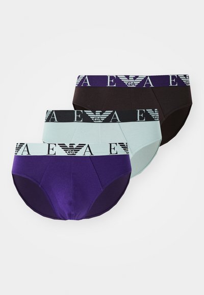 Trois paires de culottes en coton : violet foncé, noir et bleu clair. Chacune possède une ceinture élastique avec un motif de logo.