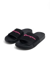 Chanclas negras con una correa perforada y el logo rosa de "Champion". Plantilla texturizada y suela lisa. Diseño minimalista, estilo de punta abierta.