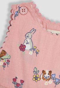 Un mono de tela rosa con bordes en forma de onda, que presenta coloridos estampados de animales y flores, incluyendo un conejo, una tortuga y un cobayo.