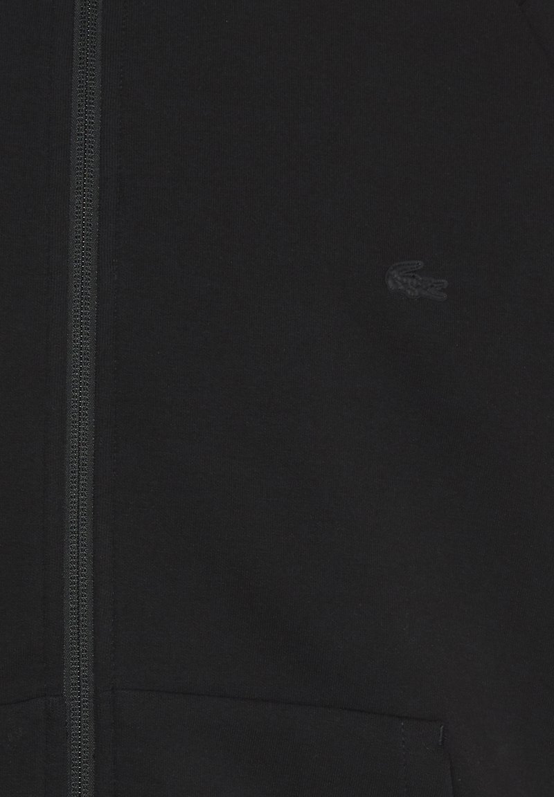 Felpa con zip nera realizzata in morbido cotone, con un tessuto testurizzato, due tasche frontali e un discreto logo ricamato sul petto.