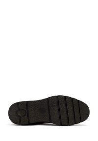 Suela de zapato de goma negra con superficie texturizada, con ranuras horizontales y un emblema circular. El diseño es plano y con bordes redondeados.