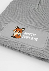 Gray knit beanie with a woven patch featuring a stylized fox design and the text "MUTTIS PFIFFIKUS" in white. Texture is ribbed.