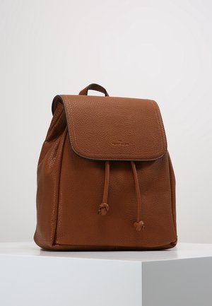 Brązowy skórzany plecak z klapą i dwoma sznurkami do ściągania, prezentowany na białym podium na tle jednolitego, jasnego tła.