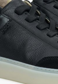 Czarne skórzane sneakersy z teksturowanym wierzchem, gładkimi akcentami, czarnymi sznurowadłami oraz białą gumową podeszwą z kontrastującymi detalami zszycia.
