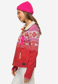 Giacca in pile rossa con yoke stampato bianco e rosa, dotata di colletto in sherpa, tasche con zip e tirazip arancioni a contrasto.