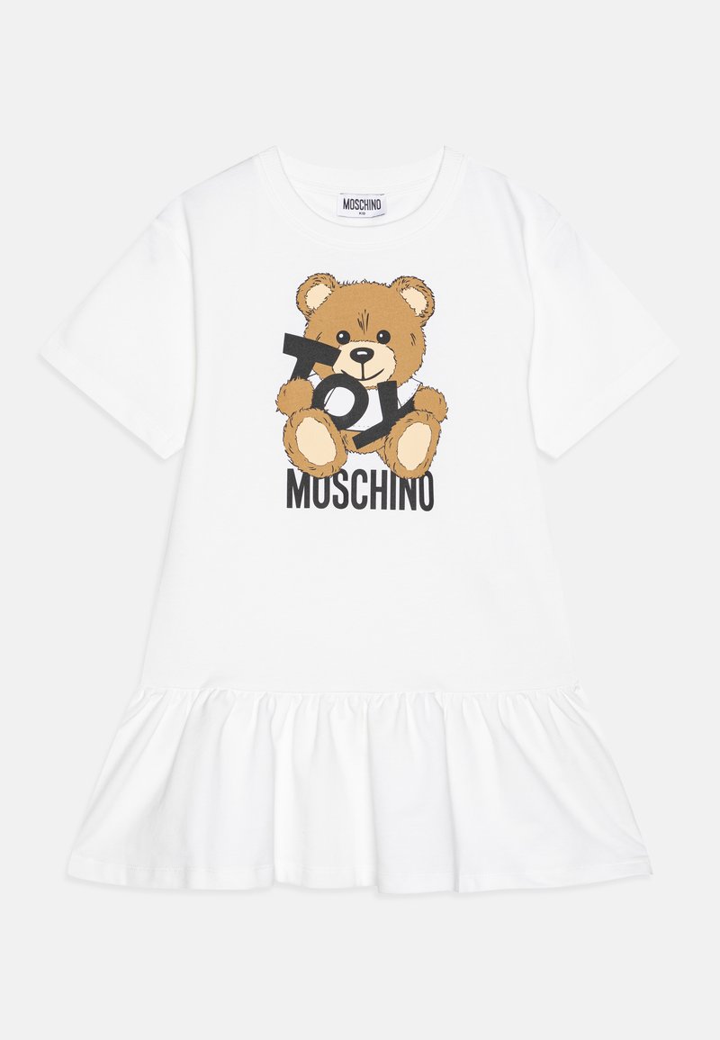 Rochie din bumbac alb cu tiv volan, decorată cu un grafic al unui ursuleț de pluș maro și textul "Toy Moschino" în negru.