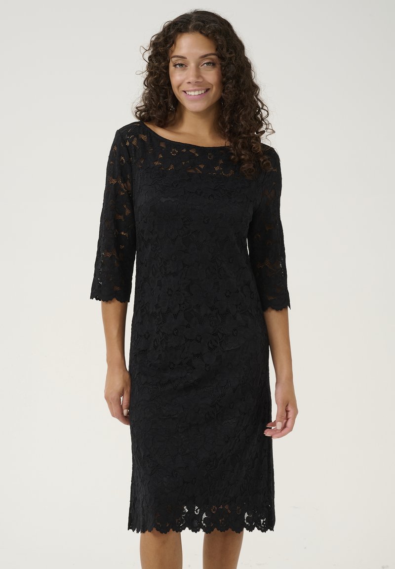 Black lace dress featuring three-quarter sleeves, floral pattern, scalloped hem, and a boat neckline. Smooth texture with intricate detailing.