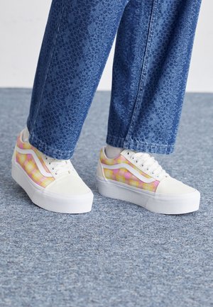 Plattform-Sneaker mit einer weißen Canvas-Zehe, mehrfarbigem karriertem Muster in Pink und Gelb sowie weißen Gummisohlen. Strukturierte Denim-Hosen.