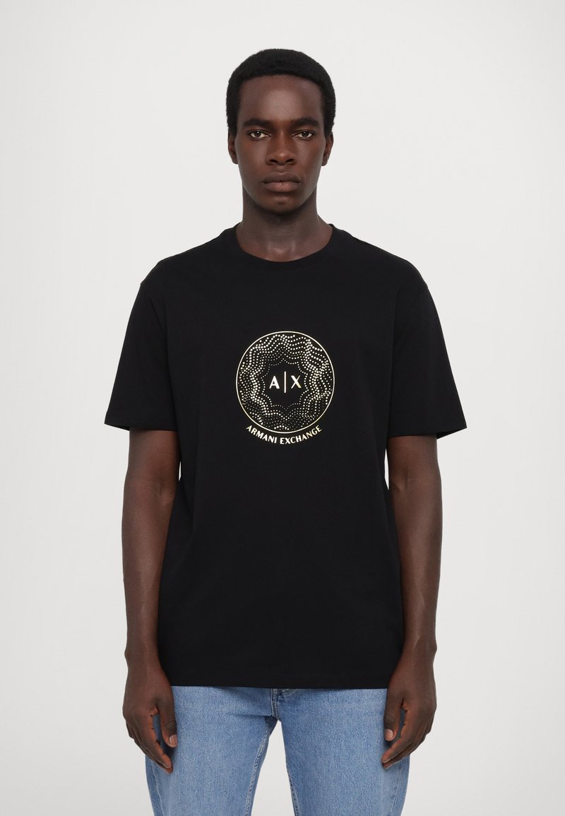 T-shirt en coton noir avec un logo rond doré portant le texte « A|X » et « ARMANI EXCHANGE », manches courtes et coupe décontractée.