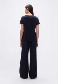 Μπλε ναυτικό κοντομάνικο t-shirt από βαμβάκι, με στρογγυλή λαιμόκοψη. Συνδυασμένο με τζιν παντελόνια φαρδιάς γραμμής, που δείχνουν casual εφαρμογή.