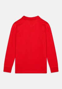 Rode poloshirt met lange mouwen en een klassieke kraag, ribgebreide manchetten en een zachte katoenen textuur. De achterkant vertoont geen grafische details of patronen.