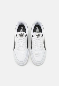 White athletic shoes with black accents, smooth synthetic material, round toe, perforated detailing, and branded tongue label.