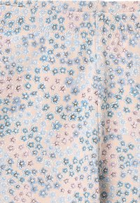 Tela beige con un pequeño estampado floral en azul, lavanda y blanco, distribuido de manera uniforme sobre la superficie.