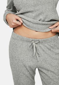 Ensemble de détente gris à côtes comprenant un haut à manches longues et un pantalon à taille élastique avec cordon de serrage. Texture douce avec un ajustement confortable.