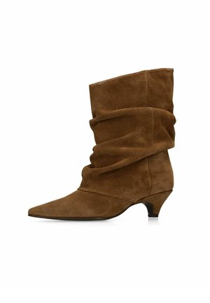 Brauner Wildleder-Stiefeletten mit schlaffen Schaft, spitzer Zehenform und niedrigem Kittenabsatz auf weißem Hintergrund.