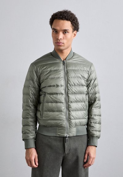 Lätt olivgrön puffjacka med horisontell kviltad design, framdragkedja, ribbade ärmslut och nederkant samt sidofickor.