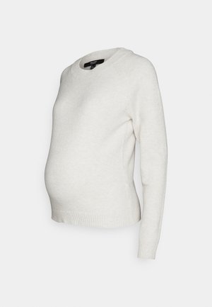 Vaaleanbeige äitiysneule, jossa on V-aukko, pitkät raglan-hihat ja ribbineulospääntie. Pehmeä neulostekstuuri, suunniteltu mukavaa istuvuutta varten.