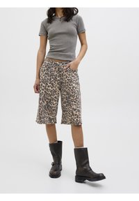 Haut gris à manches courtes côtelé associé à un short beige à motif léopard, avec deux poches avant et des bottes beiges à motifs à boucles.