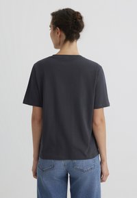 Dark gray cotton t-shirt with short sleeves, a round neckline, and a relaxed fit. The back view shows a smooth texture and simple design.