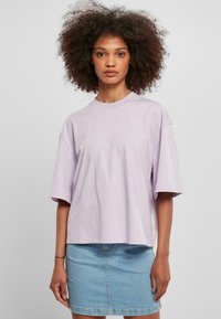 Levandulové oversized tričko s krátkými rukávy a kulatým výstřihem, vyrobené z měkké látky. V kombinaci se světle modrou denimovou mini sukní.